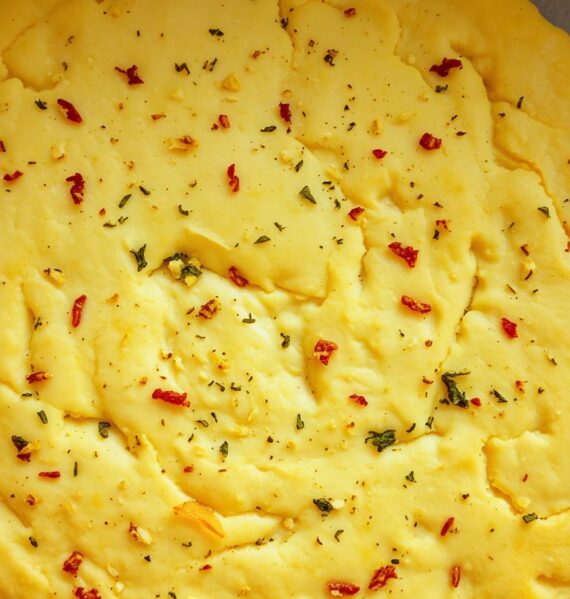 A freshly baked, golden-brown pizza dough, its surface dotted with flecks of minced garlic and fragrant herbs. The dough's texture is slightly chewy, with a faint aroma of yeast wafting through the air. The camera angle captures the dough from an overhead perspective, highlighting its circular shape and the intricate patterns created by the ingredients. Soft, natural lighting casts a warm glow, accentuating the dough's inviting appearance. The background is slightly blurred, allowing the pizza dough to take center stage and entice the viewer to imagine the delicious possibilities of this flavorful foundation for a homemade pizza.